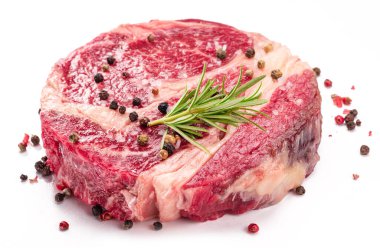 Beyaz arka planda pişmeye hazır baharatlı ve otlu çiğ biftek..