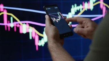 Tüccar veya yatırımcı telefon ve bilgisayar üzerinden borsa veya kripto pazar grafikleri veya grafikleri izliyor veya bakıyor. PS ekranının önündeki grafiklerle el ele tutuşan insanlar.