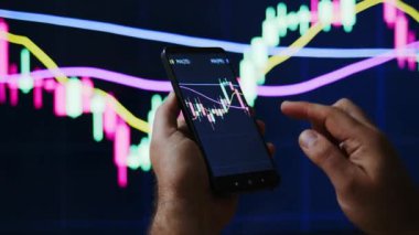 Tüccar veya yatırımcı telefon ve bilgisayar üzerinden borsa veya kripto pazar grafikleri veya grafikleri izliyor veya bakıyor. PS ekranının önündeki grafiklerle el ele tutuşan insanlar.