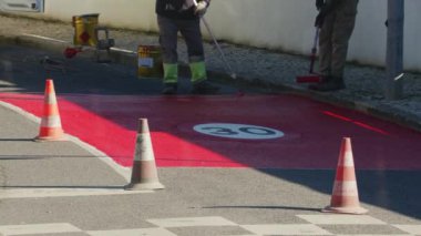 Yerleşim bölgelerinde kırmızı boya ile işaretlenen yol yüzeyinin hız sınırlandırılması için boyanma süreci. 