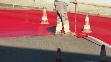 Yerleşim bölgelerinde kırmızı boya ile işaretlenen yol yüzeyinin hız sınırlandırılması için boyanma süreci. 