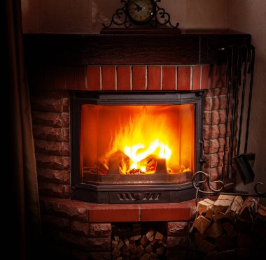 Şöminede ateş ve yanan odun. Evde ısınmanın ve rahatlamanın tatil arka planı.