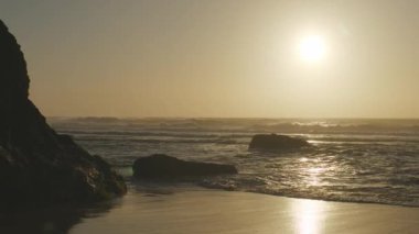 Atlantik Okyanusu 'nun Adraga plajı gün batımında, Sintra Portekiz. Güneş, su yüzeyine parlak bir yol ile yansıdı. Yavaş çekim videosu.