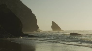 Atlantik Okyanusu 'nun Adraga plajı gün batımında, Sintra Portekiz. Güneş, su yüzeyine parlak bir yol ile yansıdı. Yavaş çekim videosu.