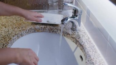Lavaboda akan suyun altında sabunla ellerini yıkamak. Hastalıkların bulaşmasını önlemek için günlük rutin işlemler önemlidir. 