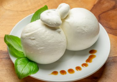 Bir top mozzarella ya da ahşap arka planda taze fesleğen yapraklı burrata peyniri..