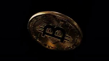 Siyah arka planda Bitcoin logosu etrafında dönen fiziksel altın kaplama sikke. Döngülü video.