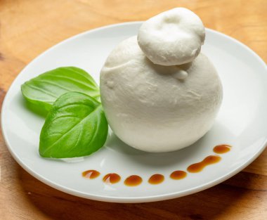Bir top mozzarella ya da ahşap arka planda taze fesleğen yapraklı burrata peyniri..