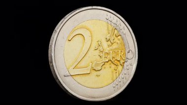 İki avroluk madeni para siyah arka planda kendi ekseni etrafında dönüyor.
