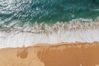 Gök mavisi okyanus suyu ve okyanus köpüğü güzel uzun kumlu plajı kaplıyor, hava aracı manzarası. Güzel doğa arkaplanı.
