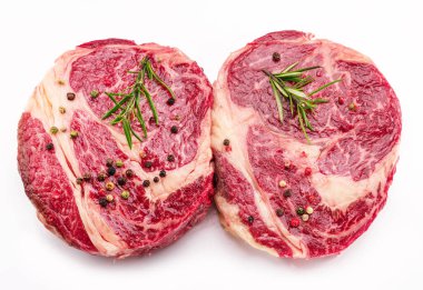 Beyaz arka planda pişmeye hazır baharatlı ve otlu çiğ biftek..