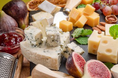 Meyve, nane, fındık ve peynir kesme bıçaklarıyla dilimlenmiş peynir çeşitleri. Projeleriniz için harika peynir arkaplanı.