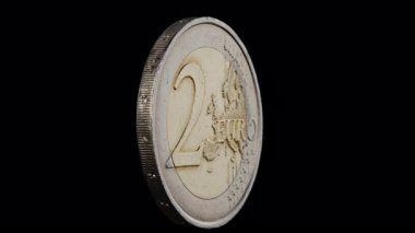  2 avroluk bozuk para siyah arkaplanda kendi ekseni etrafında dönüyor.