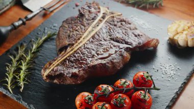 Biftek, otlar, sarımsak ve domateslerle servis panosuna yakın çekim. Üst görünüm.