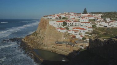 Okyanus kıyıları gün batımında Azenhas 'ta Mar, Portekiz, Sintra yakınlarındaki Colares bölgesinde. Azenhas do Mar Portekiz 'de popüler bir turizm merkezidir. Kırmızı çatıları olan güzel beyaz evler görünür..