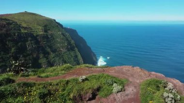 Mavi okyanus dalgaları kayalık bir kıyı şeridine yaklaşırken beyaz köpük oluştururken drone görüntüsü.