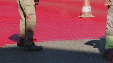 Yerleşim bölgelerinde kırmızı boya ile işaretlenen yol yüzeyinin hız sınırlandırılması için boyanma süreci. 