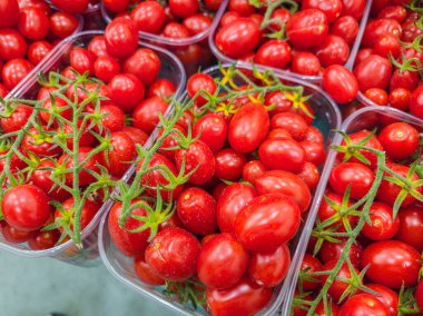 Plastik kutulardaki kırmızı kiraz domatesleri çiftlik tezgahının orada. Gıda arkaplanı.