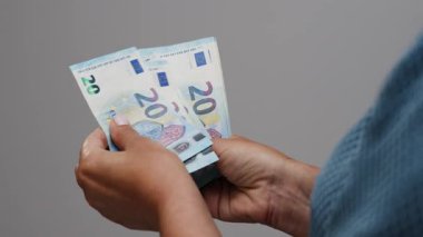 Tanımlanamayan bir kadın 20 dolarlık banknotları yakından sayıyor.