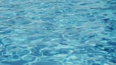 Havuzun suyunda dalgalanmalar. Şeffaf, ışıl ışıl ve hareketli suyun davetkar yüzeyi. Yukarıdan bak. Yavaş çekim videosu.