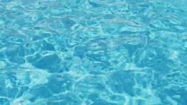 Havuzun suyunda dalgalanmalar. Şeffaf, ışıl ışıl ve hareketli suyun davetkar yüzeyi. Yukarıdan görüntüle. 