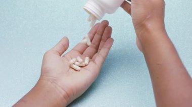Beyaz kapsüller ya da plastik şişeden açık gri arka plana dökülen haplar. İlaç, sağlık, takviye ve ilaç tedavisi kavramı.