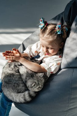 Küçük kız yatakta onu yavru kedi ile rahatlatıcı. Çocuk bir kedi öpüyor