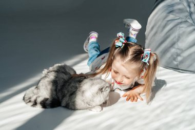 Küçük kız yatakta onu yavru kedi ile rahatlatıcı. Çocuk bir kedi öpüyor