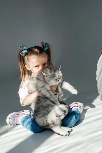 小女孩和她的小猫在床上放松 孩子正在亲吻一只猫 — 图库照片