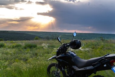 Enduro motosikleti vadinin önündeki tepede dramatik bir günbatımı ile