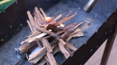 Adamın eli balta bıçağıyla şenlik ateşi için odun kırıntıları yapıyor.
