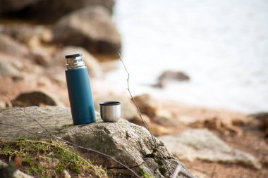 Göl kenarındaki taşın üzerindeki termos.