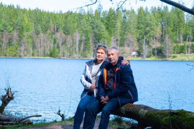 Son sınıflardan birkaçı mavi gölün yanındaki kütüğün üzerinde oturuyorlar.