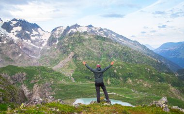 Yürüyüş yapan bir adam yaz Alpleri 'nde buzullar, göl ve dağların tepeleri karla kaplı olduğu için sevinir. Yürüyüş ve seyahat kavramı