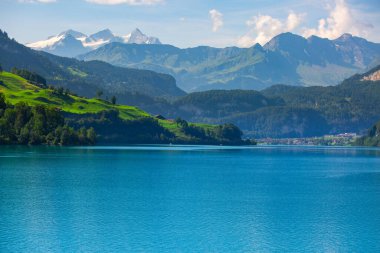 Karlı zirveleri olan yüksek dağlarla çevrili küçük mavi bir göl. seyahat ve balıkçılık kavramı