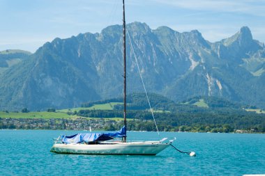 Mavi Thun gölünde, dağların önünde küçük bir yat.