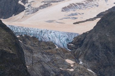 Üzerinde çatlaklar ve kar tarlaları olan mavi bir buzuldan. Kayalık dağlarda. tırmanma ve yürüyüş konsepti