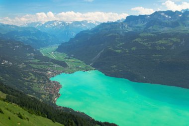 Turkuaz gölün havasından ve kıyıdaki köyden bir günlük görüntü yüksek dağlar, seyahat ve vaksiyon konseptiyle çevrili.