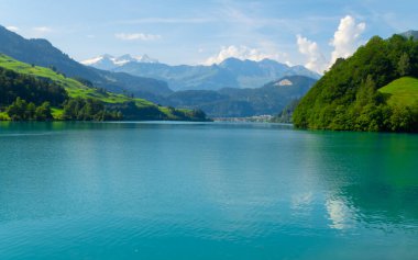 Karlı zirveleri olan yüksek dağlarla çevrili küçük mavi bir göl. seyahat ve balıkçılık kavramı