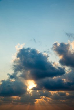 Güneş ışınlarıyla gün batımı, bulutlarla gökyüzü ve güneş.