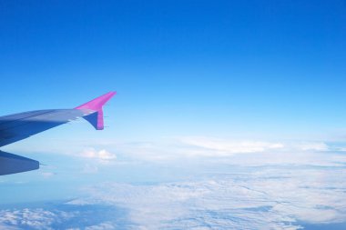 Bulutların mavi gökyüzü ve uçağın kanat manzarası uçak penceresinden.