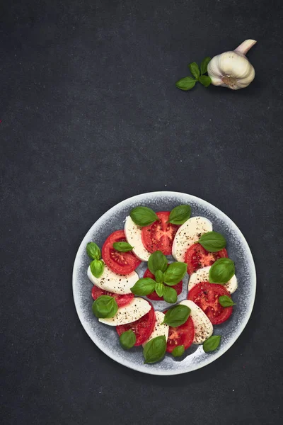 Taze vişneli domates, fesleğen, siyah taş masada mozzarella peyniri. Sağlıklı İtalyan geleneksel salata malzemeleri. Organik Akdeniz mutfağı konsepti, daire, yakın plan. Yaz Yemeği.