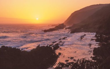 Güney Afrika 'daki Tsitsikamma Ulusal Parkı' nda popüler su samuru patikasının başlangıcında gün batımı.