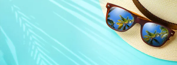concept vacation and summer travel banner. Happy holidays on sandy tropical sea beach. Panama hat and sunglasses with a reflection of the sandy trovic beach and palm trees