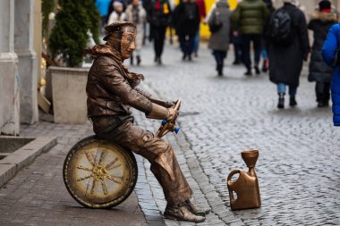 Vilnius, Litvanya - 16 Şubat 2023: Pilies Street 'te bir sokak oyuncusu sahne aldı. Kendisini yaşayan bir heykele dönüştürdü. Baştan ayağa bronzla boyandı.. 