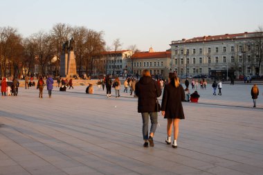 Vilnius, Litvanya - 19 Mart 2022: Sonbaharda Vilnius şehrinin ufuk çizgisi: günbatımında Liepkalnis Hill, SkVilnius Katedral Meydanı manzarası: bahar gününün keyfini çıkaran insanlar.