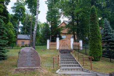 Slavikai, Lithuania - June 2, 2023: Slavikai St. Anna's church and memorial stone in Slavikai village, Sakiai district.  clipart