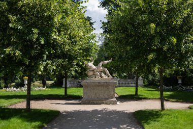 Trakai, Lithuania - June 16, 2024: Classical marble statue of Bachus surrounded by lush greenery in Uzutrakis manor park. Sculptors R. and N. Kavaliauskai, 2011. clipart