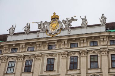 Avusturya, Viyana 'daki Hofburg Sarayı' nın barok mimari detayları, çatıda süslü heykeller ve altın imparatorluk arması bulunuyor.