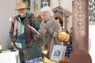 Vilnius, Litvanya - 8 Mart 2025: Litvanya 'nın Vilnius kentindeki Kaziukas fuarında el yapımı ahşap horoz ve halk sanatı satan yaşlı zanaatkar.